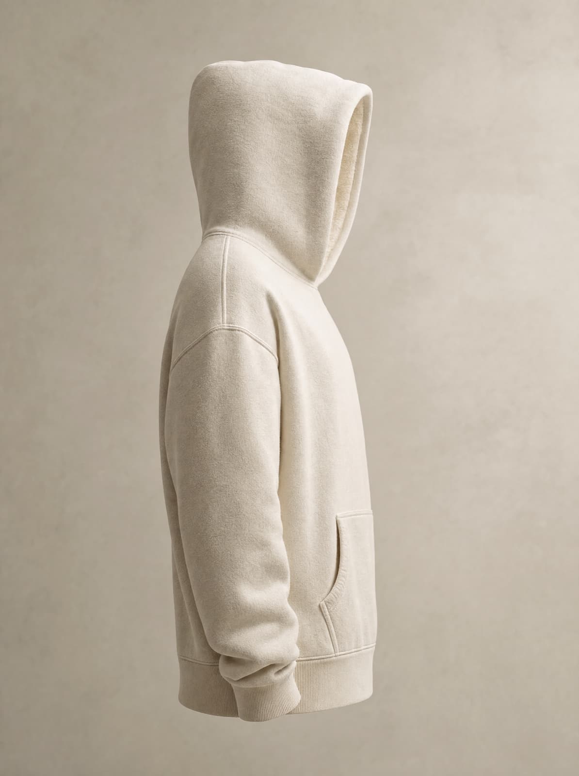 Cream heavyweight hoodie — side profile, hood up, fleece texture readable
